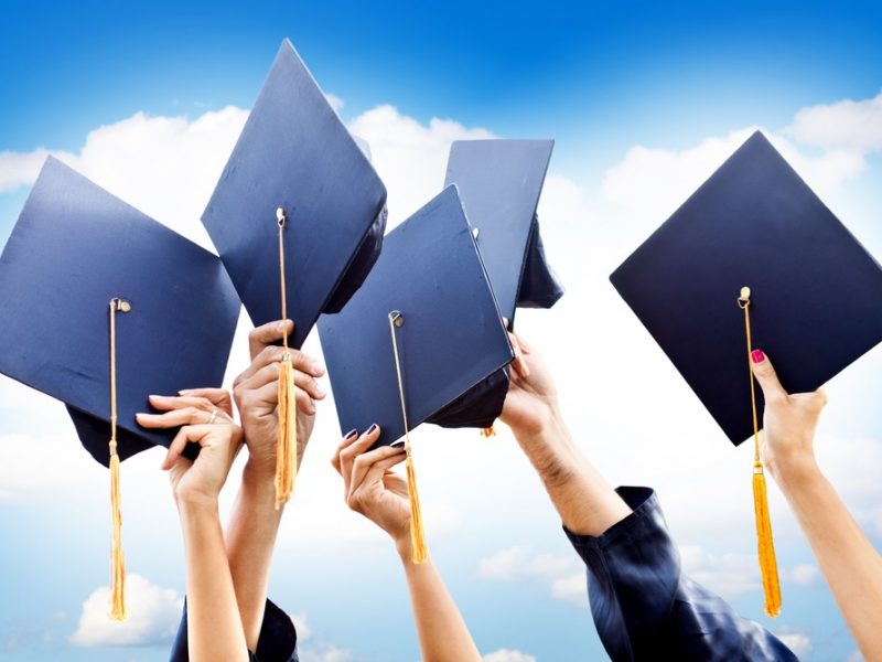 Unrecognizable group of people throwing graduations hats in the air